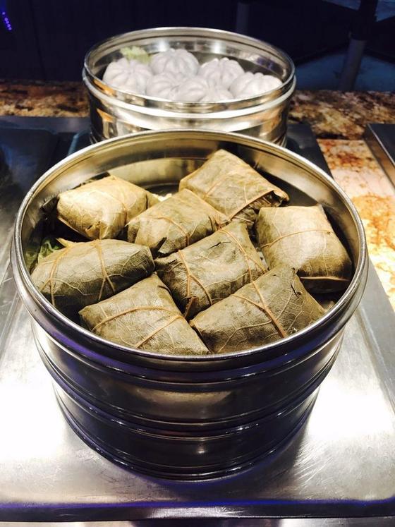 Sticky rice wrapped in lotus leaves, with steamed buns behind